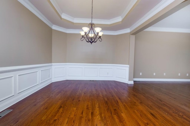 spare room with ornamental molding, dark hardwood / wood-style flooring, a raised ceiling, and a notable chandelier