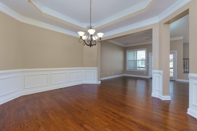 spare room with a raised ceiling, ornamental molding, dark hardwood / wood-style floors, and a chandelier