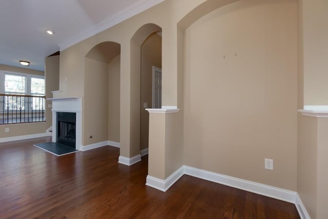 unfurnished living room with dark wood-type flooring and ornamental molding