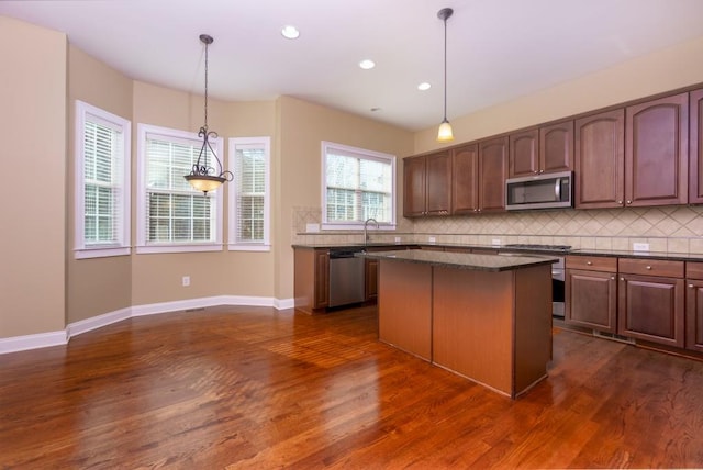 kitchen featuring stainless steel appliances, decorative light fixtures, a center island, and decorative backsplash