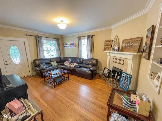 living room with ornamental molding, a tile fireplace, and hardwood / wood-style floors