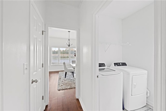 clothes washing area with a notable chandelier, washer and dryer, and dark hardwood / wood-style flooring