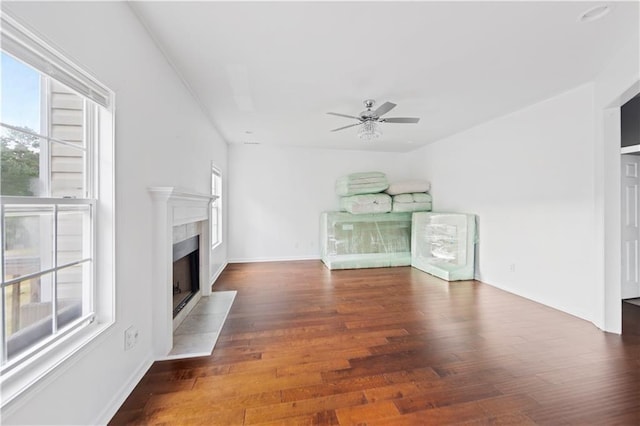 unfurnished living room featuring a tile fireplace, dark hardwood / wood-style floors, and ceiling fan