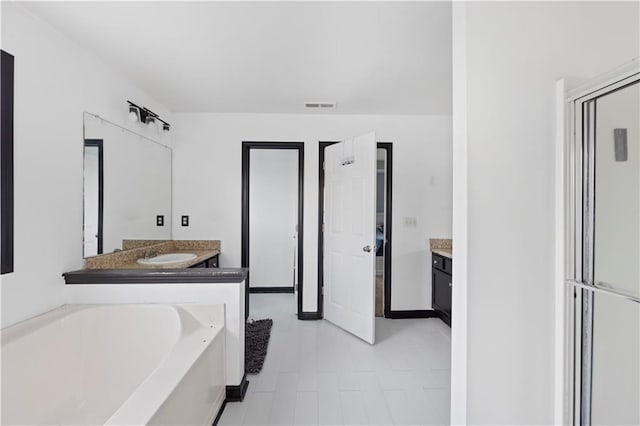 bathroom with a bath, vanity, and tile patterned floors