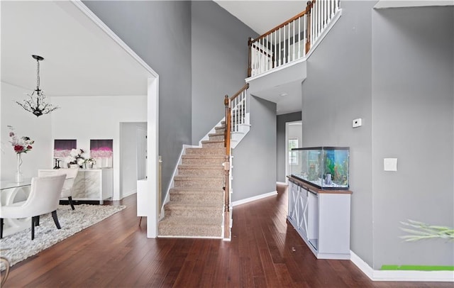 staircase with hardwood / wood-style flooring, a high ceiling, and a chandelier