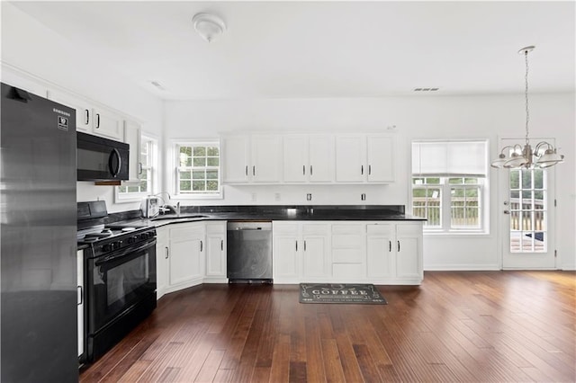 kitchen with black appliances, decorative light fixtures, white cabinetry, and dark wood-type flooring