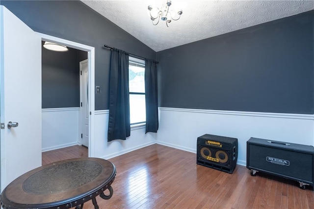 misc room with lofted ceiling, a textured ceiling, an inviting chandelier, and dark hardwood / wood-style floors