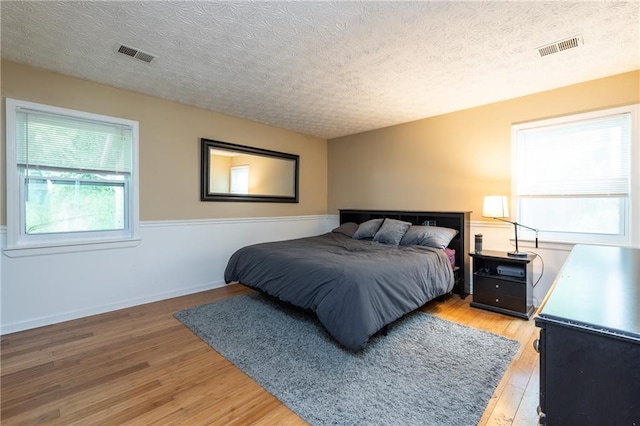 bedroom with a textured ceiling and wood-type flooring