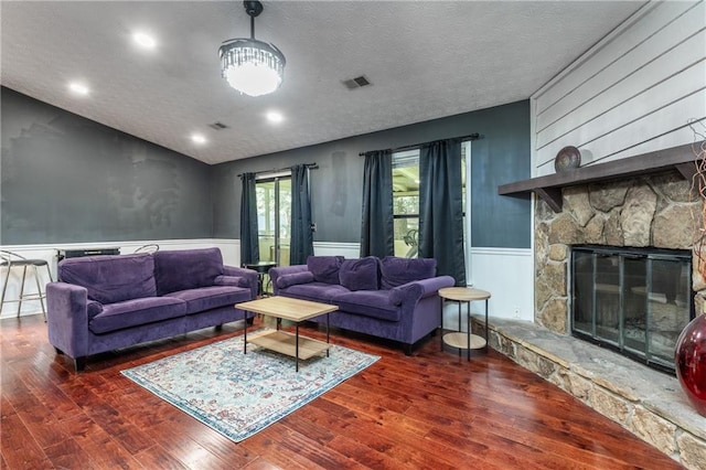 living room with a fireplace, dark wood-type flooring, and a textured ceiling