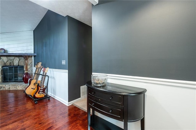 interior space with dark wood-type flooring and a stone fireplace