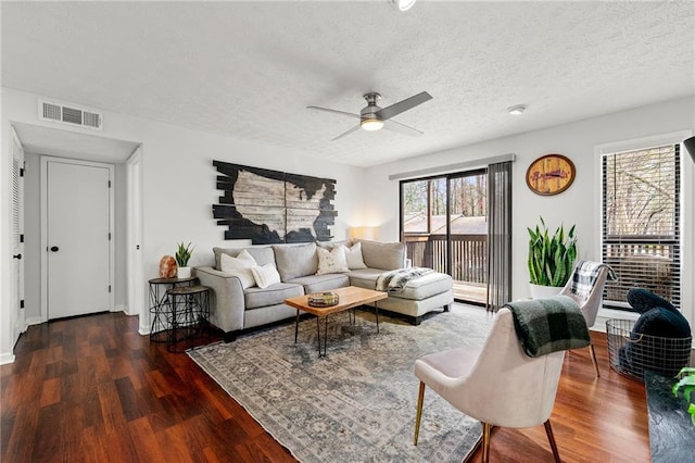 living area featuring visible vents, a textured ceiling, wood finished floors, and a ceiling fan