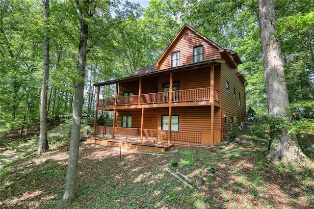 rear view of house with a wooden deck and log veneer siding