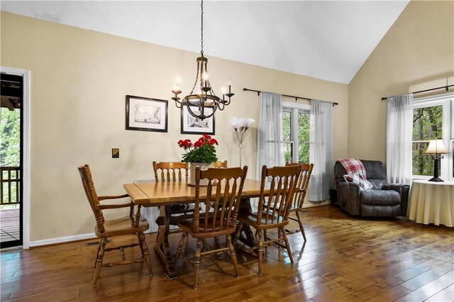 dining space with high vaulted ceiling, a notable chandelier, baseboards, and hardwood / wood-style flooring