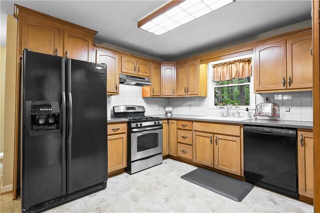 kitchen with under cabinet range hood, brown cabinets, tasteful backsplash, a sink, and black appliances