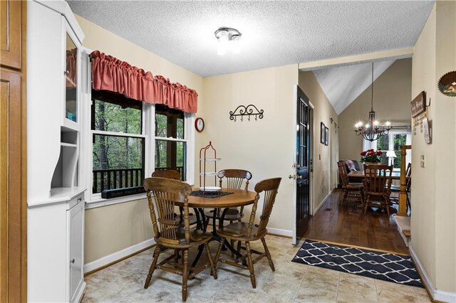 dining area with an inviting chandelier, a textured ceiling, and a wealth of natural light