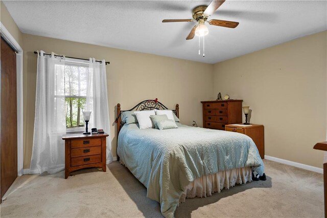 bedroom featuring a ceiling fan, baseboards, light carpet, and a closet
