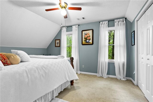 bedroom with carpet flooring, visible vents, multiple windows, and lofted ceiling