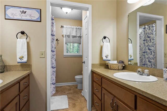 full bathroom with toilet, tile patterned floors, baseboards, and vanity