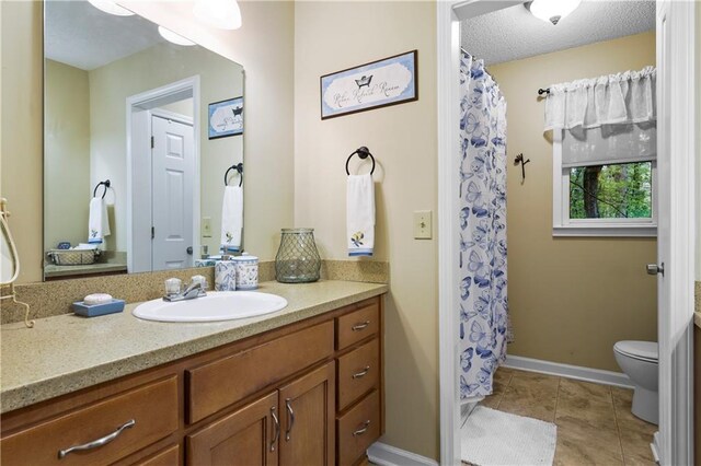 bathroom with toilet, baseboards, tile patterned floors, and vanity