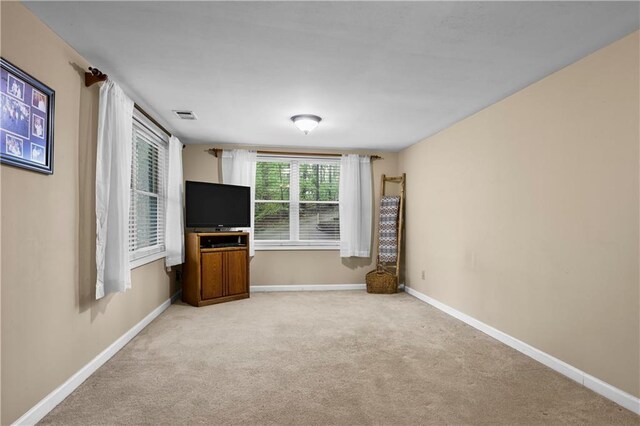 unfurnished living room featuring light colored carpet, baseboards, and visible vents