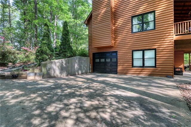 view of home's exterior with faux log siding, an attached garage, and driveway