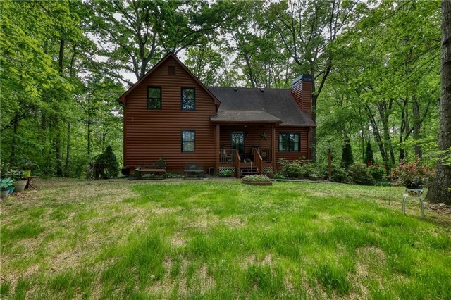 back of property with a chimney, a yard, and log veneer siding