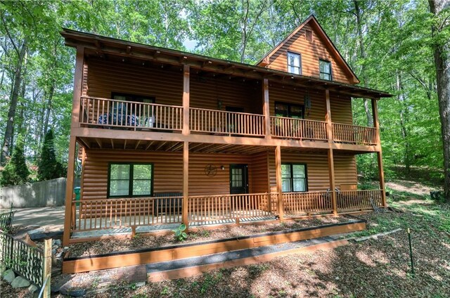 rear view of property with a balcony and faux log siding