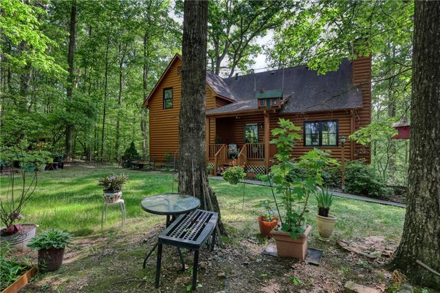 back of property with a lawn, log exterior, and roof with shingles