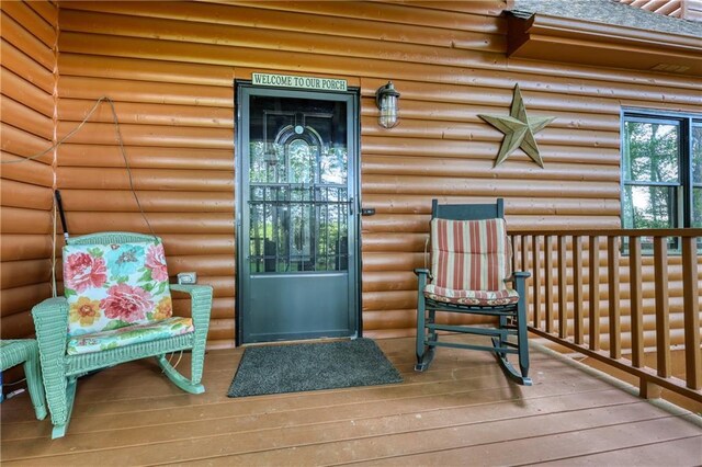 doorway to property with covered porch and log veneer siding