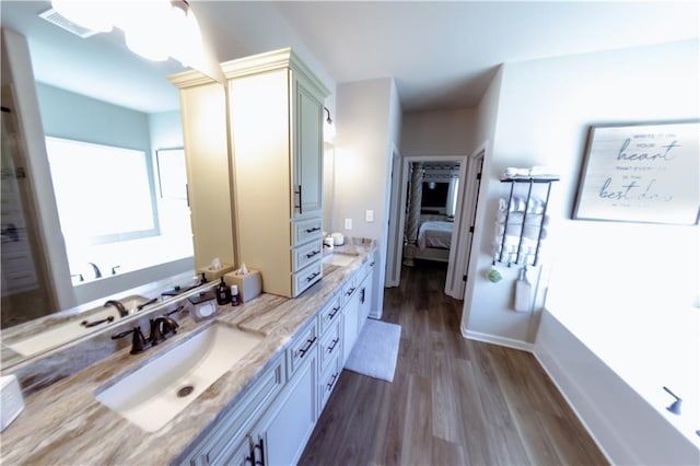 bathroom with a tub to relax in, vanity, and wood-type flooring