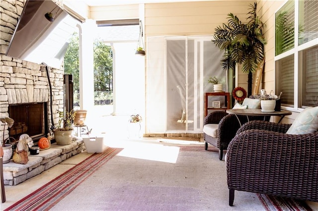 living area with an outdoor stone fireplace and carpet flooring