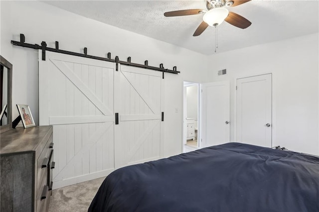 carpeted bedroom featuring vaulted ceiling, connected bathroom, ceiling fan, a barn door, and a textured ceiling