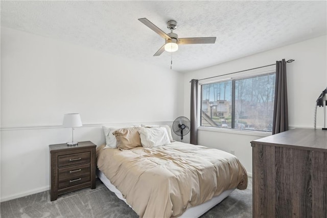 bedroom featuring dark colored carpet, ceiling fan, and a textured ceiling