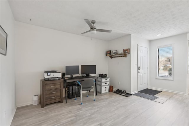 office space featuring ceiling fan, light hardwood / wood-style flooring, and a textured ceiling