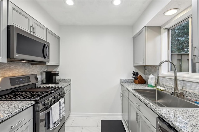 kitchen featuring gray cabinetry, sink, stainless steel appliances, and light stone countertops