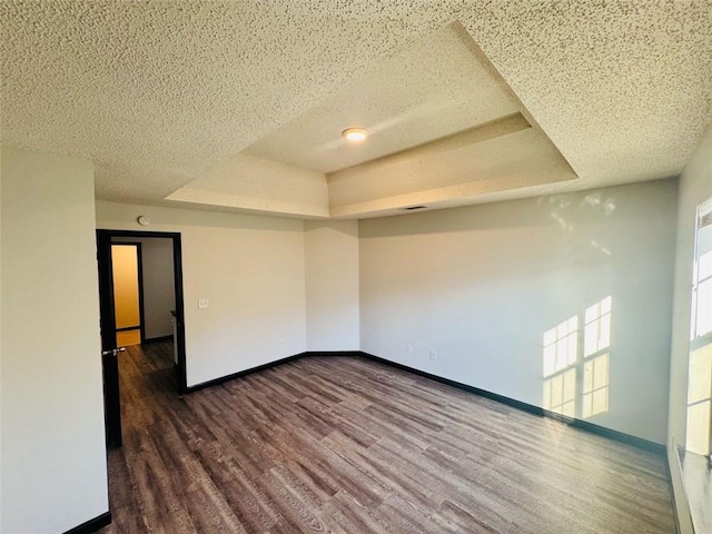 225 Colser Dr, Covington, GA 30016 - empty room with a tray ceiling, dark wood-type flooring, baseboards, and a textured ceiling