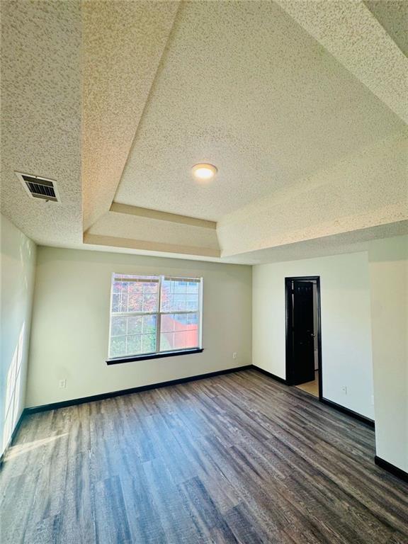 225 Colser Dr, Covington, GA 30016 - empty room with baseboards, wood finished floors, a tray ceiling, and a textured ceiling