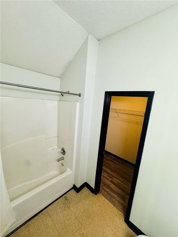 225 Colser Dr, Covington, GA 30016 - full bathroom with tile patterned floors, a textured ceiling, tub / shower combination, baseboards, and a spacious closet