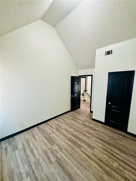 225 Colser Dr, Covington, GA 30016 - additional living space featuring wood finished floors, vaulted ceiling, a textured ceiling, and baseboards