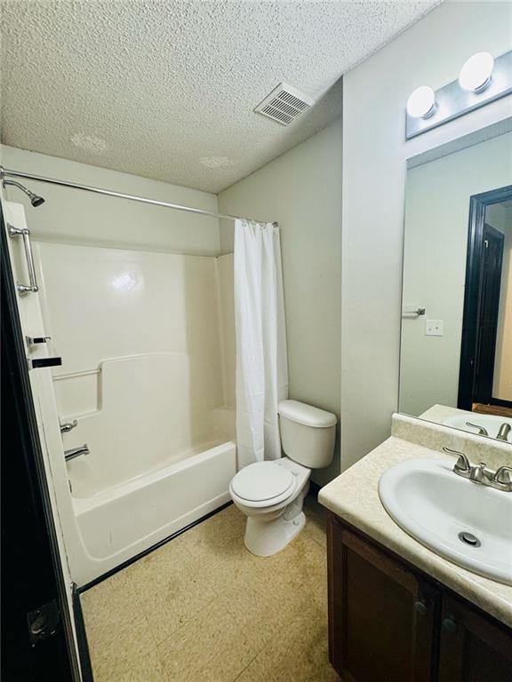 225 Colser Dr, Covington, GA 30016 - full bathroom with tile patterned floors, shower / bath combination with curtain, a textured ceiling, toilet, and vanity