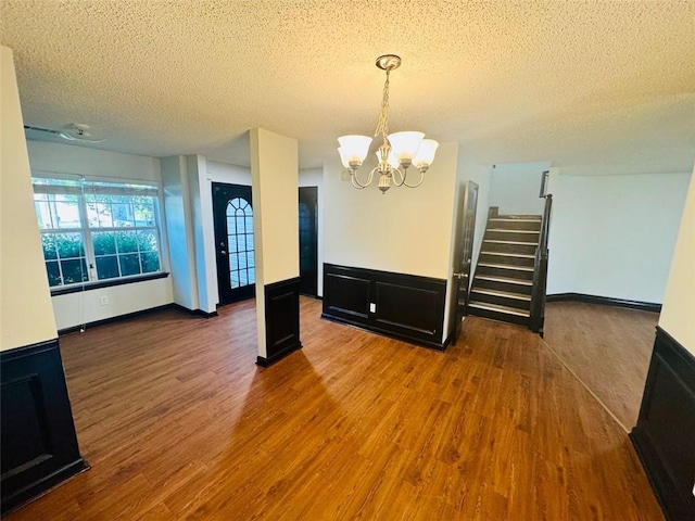 225 Colser Dr, Covington, GA 30016 - unfurnished dining area with a textured ceiling, a chandelier, wood finished floors, and stairway