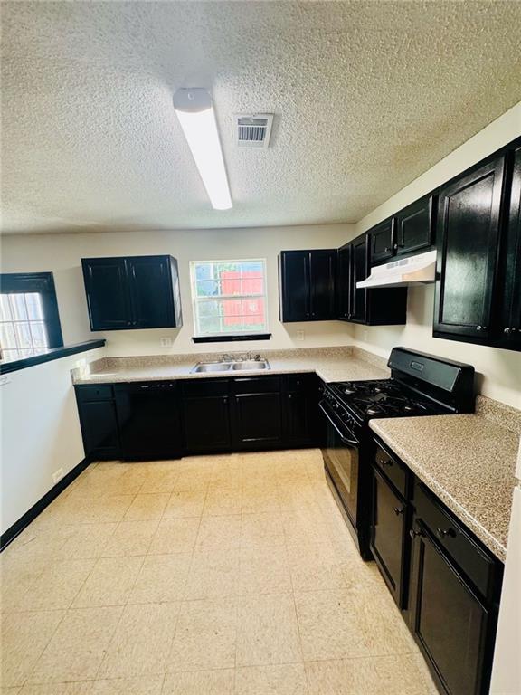 225 Colser Dr, Covington, GA 30016 - kitchen featuring black appliances, dark cabinetry, under cabinet range hood, a sink, and a textured ceiling