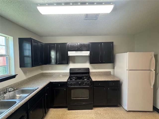 225 Colser Dr, Covington, GA 30016 - kitchen featuring black range with gas stovetop, freestanding refrigerator, dark cabinets, a sink, and under cabinet range hood