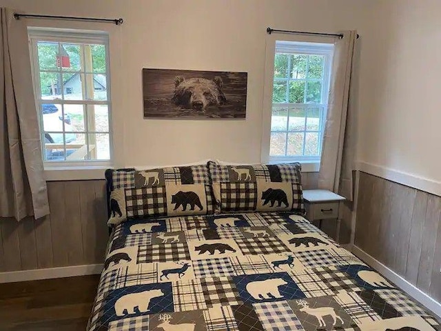 bedroom with multiple windows, wood walls, and dark wood-type flooring