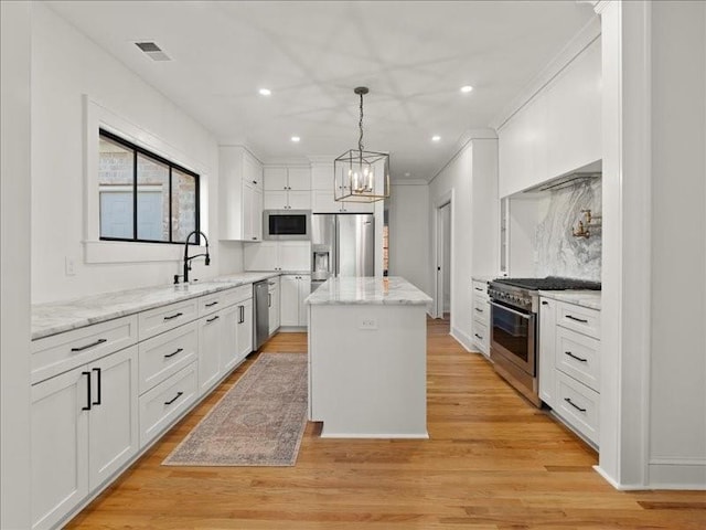 kitchen featuring stainless steel appliances, a kitchen island, a sink, visible vents, and white cabinets