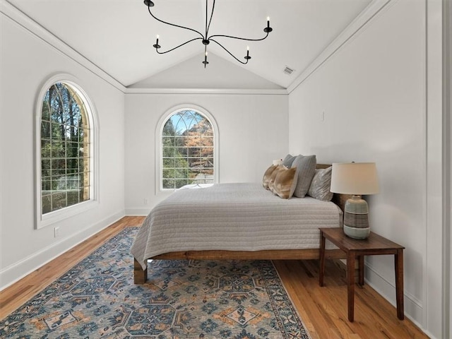 bedroom with a chandelier, wood finished floors, lofted ceiling, and visible vents