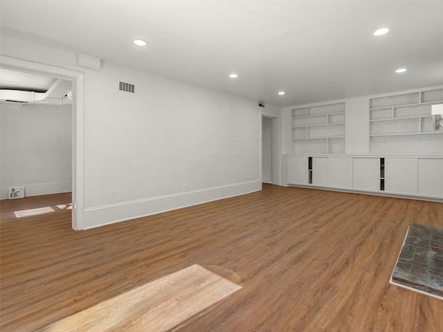 unfurnished living room with baseboards, visible vents, and wood finished floors