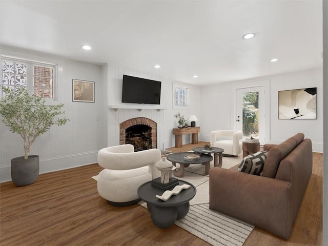 living room featuring baseboards, a brick fireplace, wood finished floors, and recessed lighting