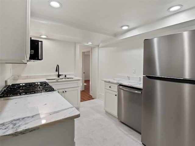 kitchen with appliances with stainless steel finishes, a sink, light stone counters, and recessed lighting