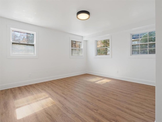 empty room featuring baseboards, a wealth of natural light, and wood finished floors